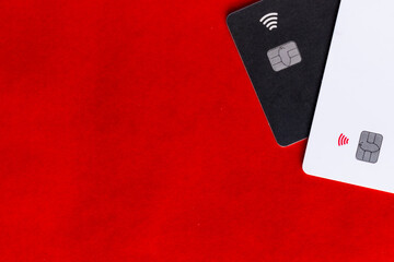 Two chip-enabled payment cards, one black and one white, placed against a vibrant red background.