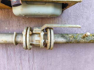 A rusty pipe with a valve on it. The valve is rusted and dirty. The pipe is old and has been...