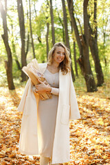 Portrait of a curly woman with baguettes outdoors in autumn park