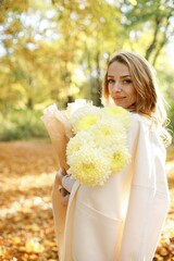 Portrait of a curly woman with yellow flowers outdoors in autumn park