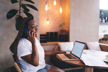 Young Black woman giving OK hand gesture during phone call, confidently managing remote work,...