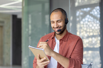 Professional customer support agent communicating with clients, taking notes, and wearing a...