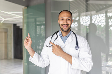 A male doctor in a modern office pointing and smiling, exuding confidence and welcome