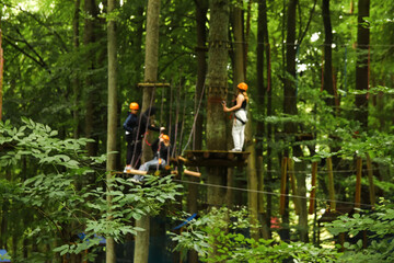 people and kids enjoying an extreme sport in a forest park. The ropeway concept. The participants are wearing helmets and using a rope for safety. Blurred. Out of focus
