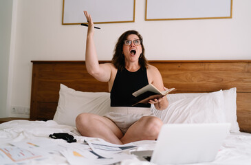 Surprised female freelancer reacts during online meeting while planning business tasks from home,...
