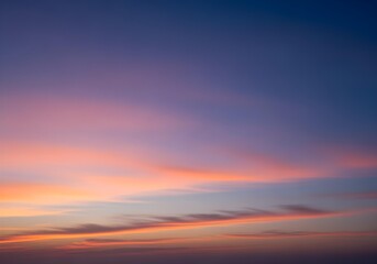 Obraz premium Vivid sunset sky with orange and pink clouds over soft gradient from warm golden horizon to deep blue, natural evening cloudscape view