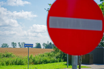 No entry road sign with left turn arrow and field behind