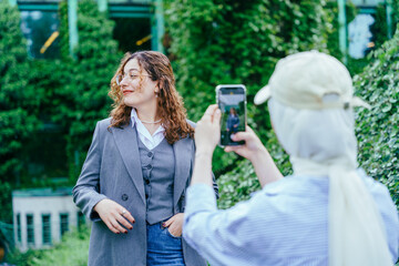 Two young women enjoying outdoor photography session near green urban architecture