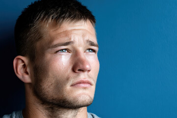 Fototapeta premium young man with tearstreaked cheeks embodies pure despair against clean solid background