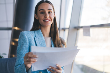 Smiling freelancer in blue blazer holds paperwork, expressing optimism, professionalism and...