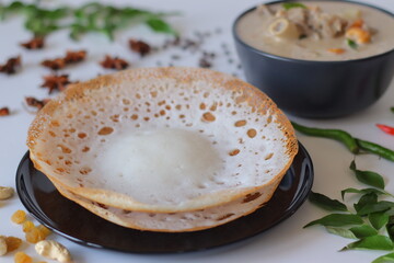 Kerala style appam with mutton stew in coconut milk gravy, styled with curry leaves, spices, and...