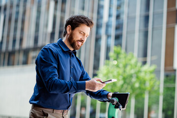 Businessman accessing mobile app for electric scooter rental alongside urban office buildings...