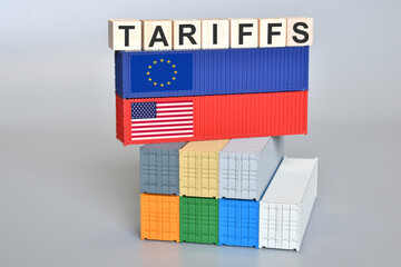 Wooden cubes with the word "Tariffs" on shipping containers with US and EU flags. An idea for a new tariff war.