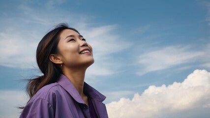 Beautiful Asian woman wearing purple refreshing outfit looking up on clear sky background, smiling while looking at the sky panoramic view
