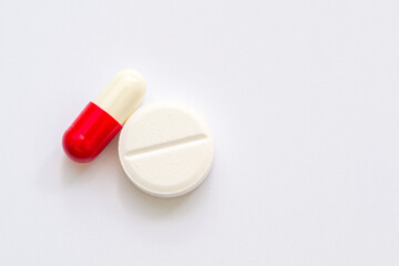 Close up shot of a capsule and a pill on a white surface symbolizing medicine and healthcare...