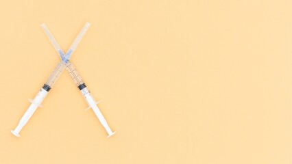 Two Syringes Crossed on a Peach Background Medical Mockup for Healthcare Professionals