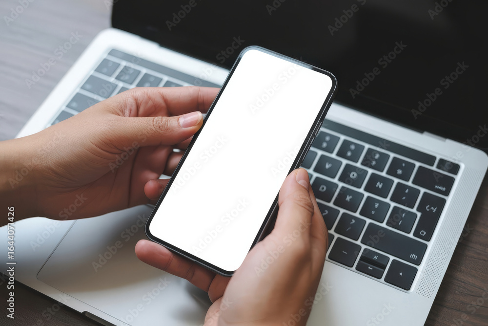 Poster a person holding a mobile phone in front of a laptop, emphasizing the connection between technology 