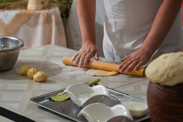 A male cook prepares dough for pies, his hands are stained with wheat flour
