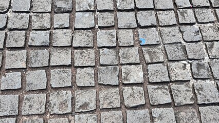 Close-up of weathered cobblestone pavement texture grey stone.