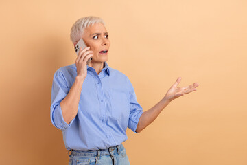 Mature woman in a blue striped shirt making a surprised gesture while talking on the phone against...