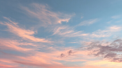 Obraz premium Delicate wispy clouds painted with soft peach and rose hues against a serene blue sky sunset twilight