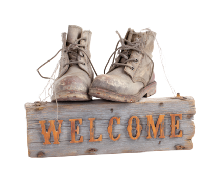 Old weathered boots resting on a rustic welcome sign.