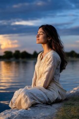 Peaceful South Asian Woman Enjoying Sunset by the Lake in Relaxed Pose Outdoors