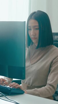 Vertical Screen : Young Asia female freelance typing write prompt AI bot IT app program nomad, video game, terminal with coding language, user interface, designer, big data center on desktop computer.