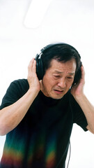 Autistic adult man wearing noise cancelling headphones on light background with facial expression of discomfort from sensory overload autism ADHD hypersensitivity