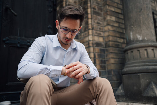 Impatient businessman checking time on wristwatch outdoors