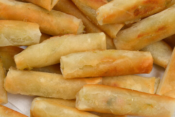 A pile of freshly fried spring rolls with a golden-brown, crispy exterior is arranged for serving