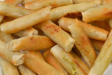 A pile of freshly fried spring rolls with a golden-brown, crispy exterior is arranged for serving
