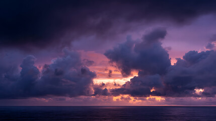 Dramatic twilight sky with vibrant purple and orange hues over a dark ocean clouds