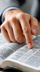 Person studying a book with detailed text and definitions while wearing a gray suit in a bright indoor setting during the day