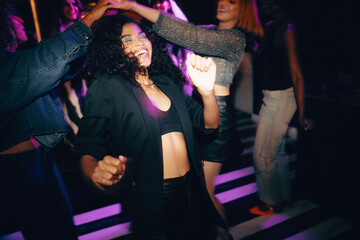 Friends dancing together under vibrant lights at a lively nightclub