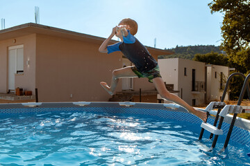Boy jumping into swimming pool in summer