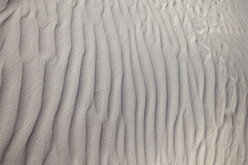 Wind blown white gypsum sand, looks like ripples in the water, frozen in time. Small waves created by the winds in White Sands National Park, Alamogordo, NM.