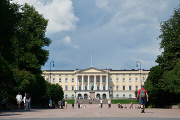 Wide Shot of Oslo Royal Palace with Tourists Walking Along Tree-Lined Boulevard on a Bright Summer Day