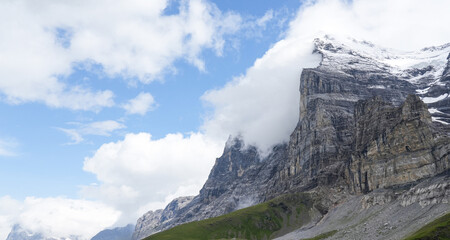 Majestic mountain landscape featuring towering cliffs, lush green valleys, and dramatic clouds, showcasing the beauty of nature in a serene outdoor environment with breathtaking views