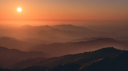 Golden sun illuminating layered mountain peaks under hazy sky sunrise mountains