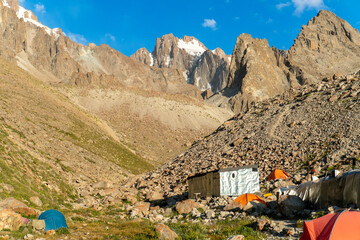Ratsek Mountain camp nestled in rocky valley beneath Korona peak, Ala-Archa Park. Tents scattered...