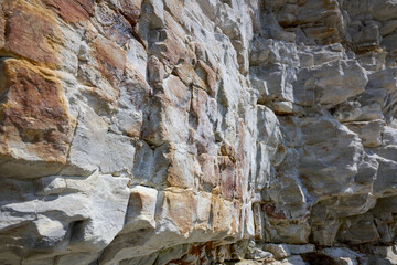 Close up of textured limestone cliff face with layered rock formations and natural color variations...