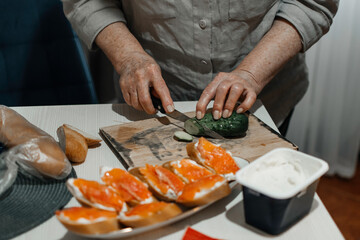 Close-up female hands make sandwiches with bread and butter or soft cheese and salmon fillets.