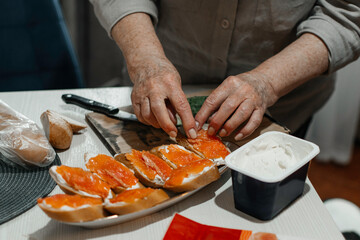Close-up female hands make sandwiches with bread and butter or soft cheese and salmon fillets.