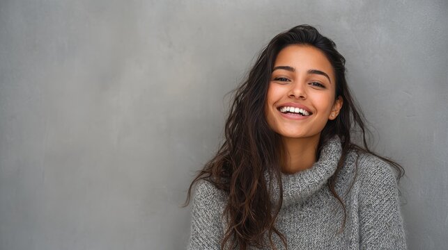 portrait of happy latin young woman isolated on grey wall with copy space carefree hispanic woman smiling and looking at camera standing on gray background beautiful multiethnic girl laughing no logo
