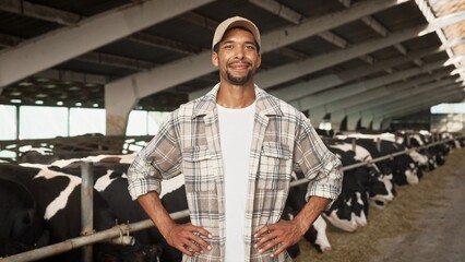 Camera moving toward happy handsome man farmer in cap standing indoor in barn and smiling to...