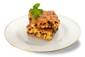 Slices of fruit cake with chocolate and orange marmalade with fresh mint leaves on a white plate with a gold border isolated
