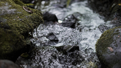 Clear stream running through stone boulders Abundant river flowing on stone bottom in slow motion. Wild mountain river water splashing in summer day.underwater bubbles. split view.