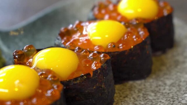 Close up of sushi with salmon roe and quail egg on a gray stone plate