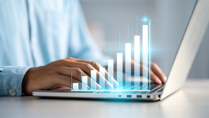 Close up of person s hands typing on a laptop with a glowing blue digital financial growth bar chart overlay